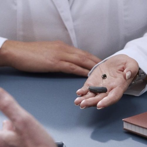 Image of a hearing aid in an audiologist's hand